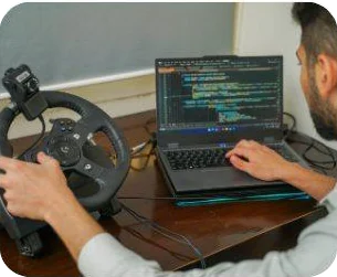 An engineer testing with a steering-wheel rig next to live code